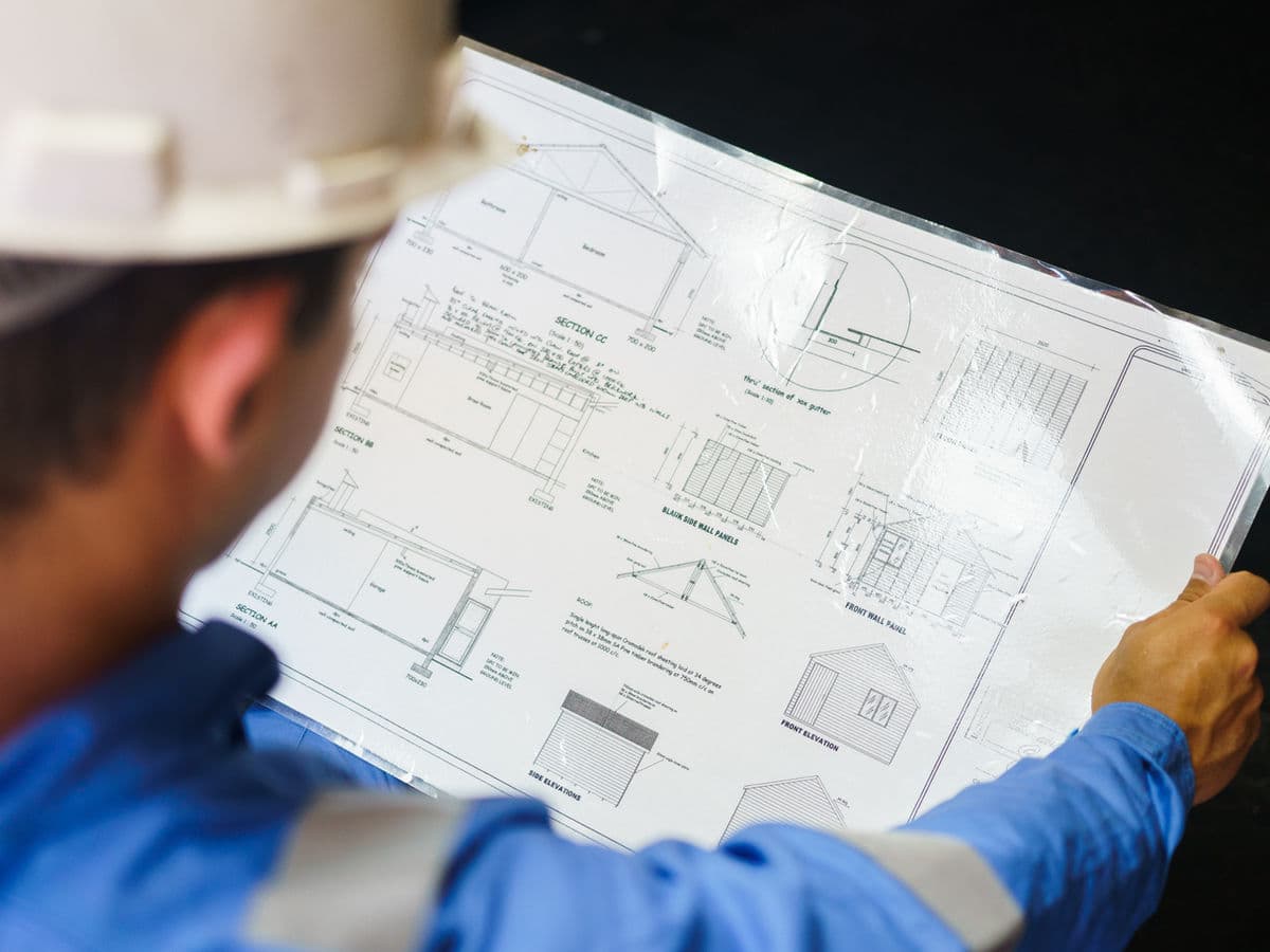 Construction worker reviewing engineering drawings for a steel building.